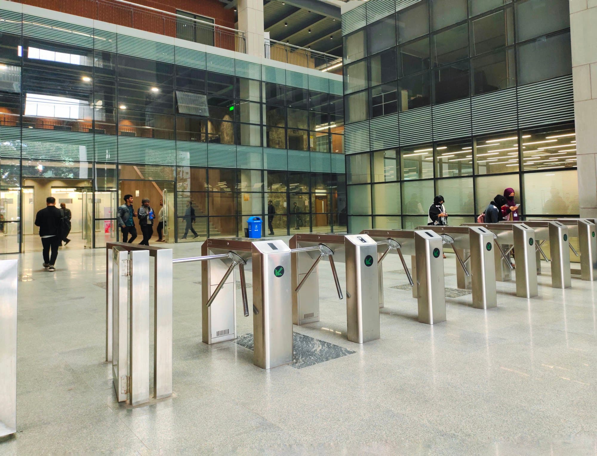 Staff walking through glass turnstiles in an office lobby
